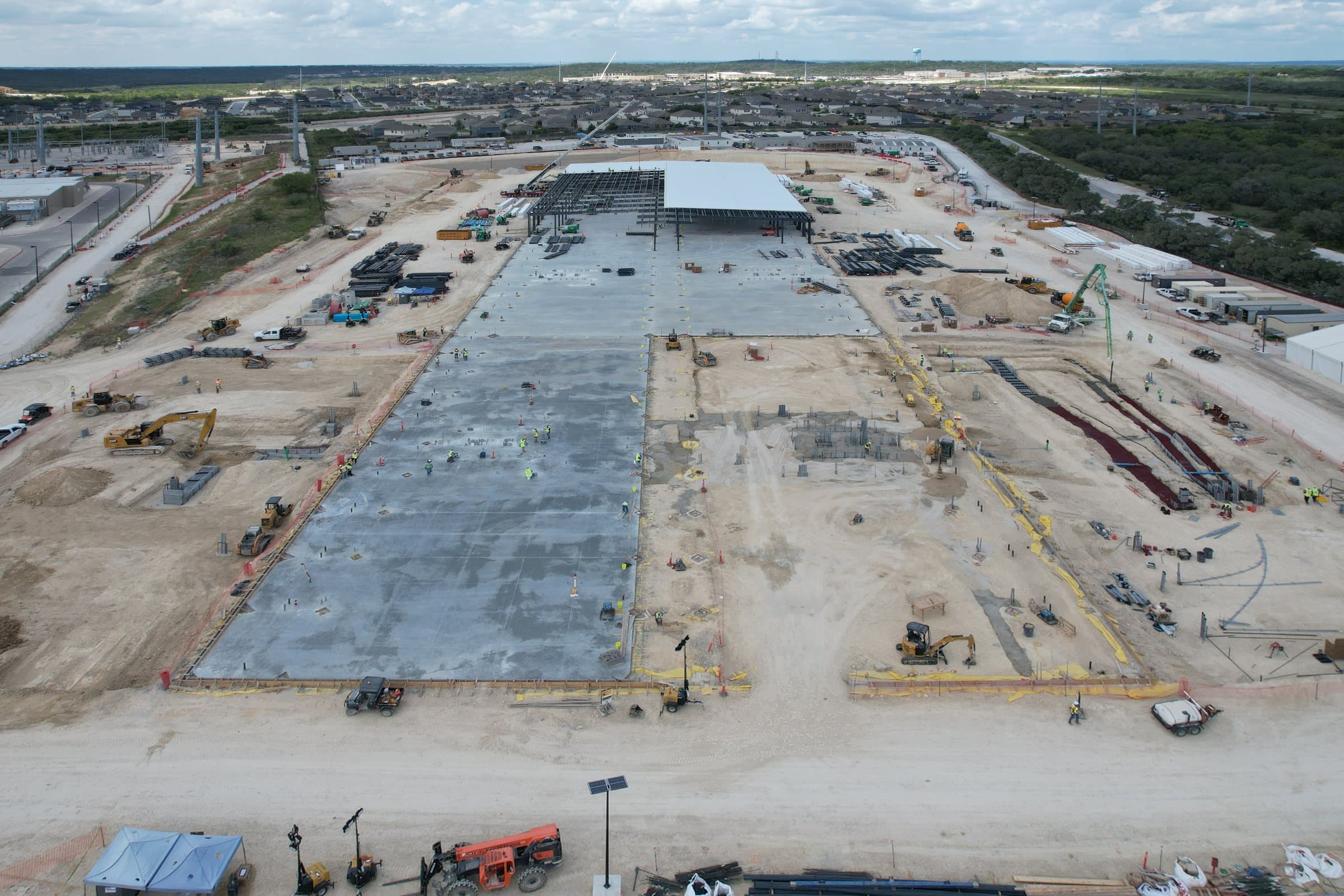 Construction site with a concrete slab poured and steel starting to rise