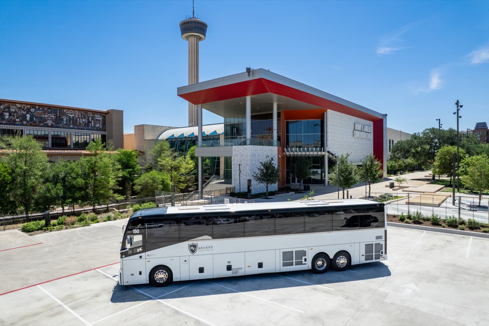 Bus in front of a modern building near the Tower of the Americas