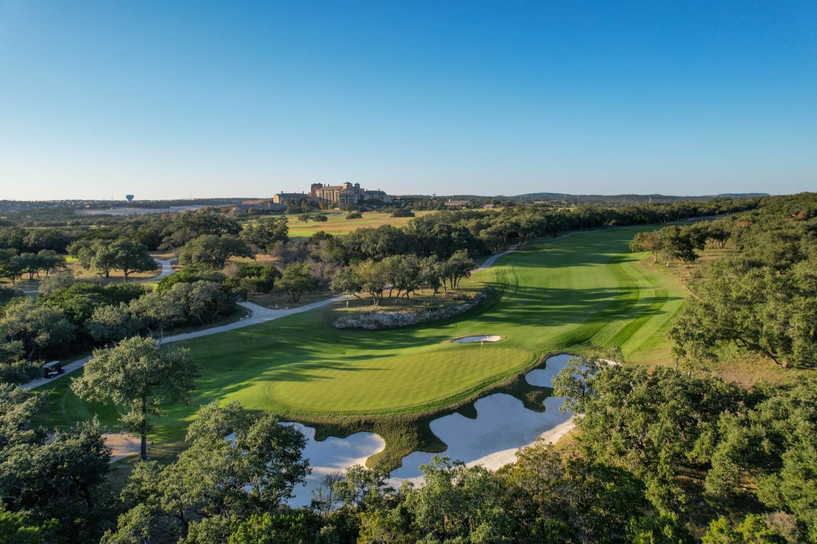 Golf hole with water hazards among oak trees