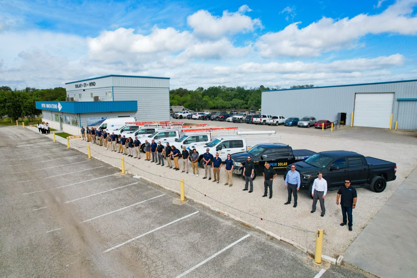 Team lined up beside trucks outside a solar company building