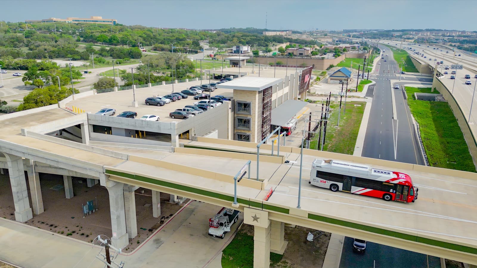 City bus on an elevated roadway beside a parking structure