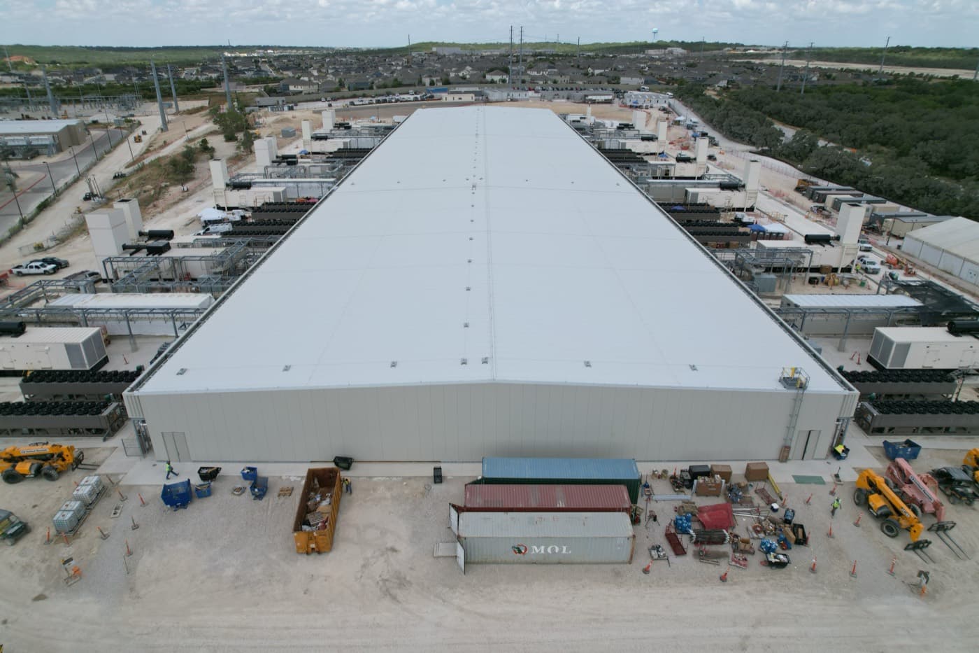 Completed large building with a white roof and equipment around it