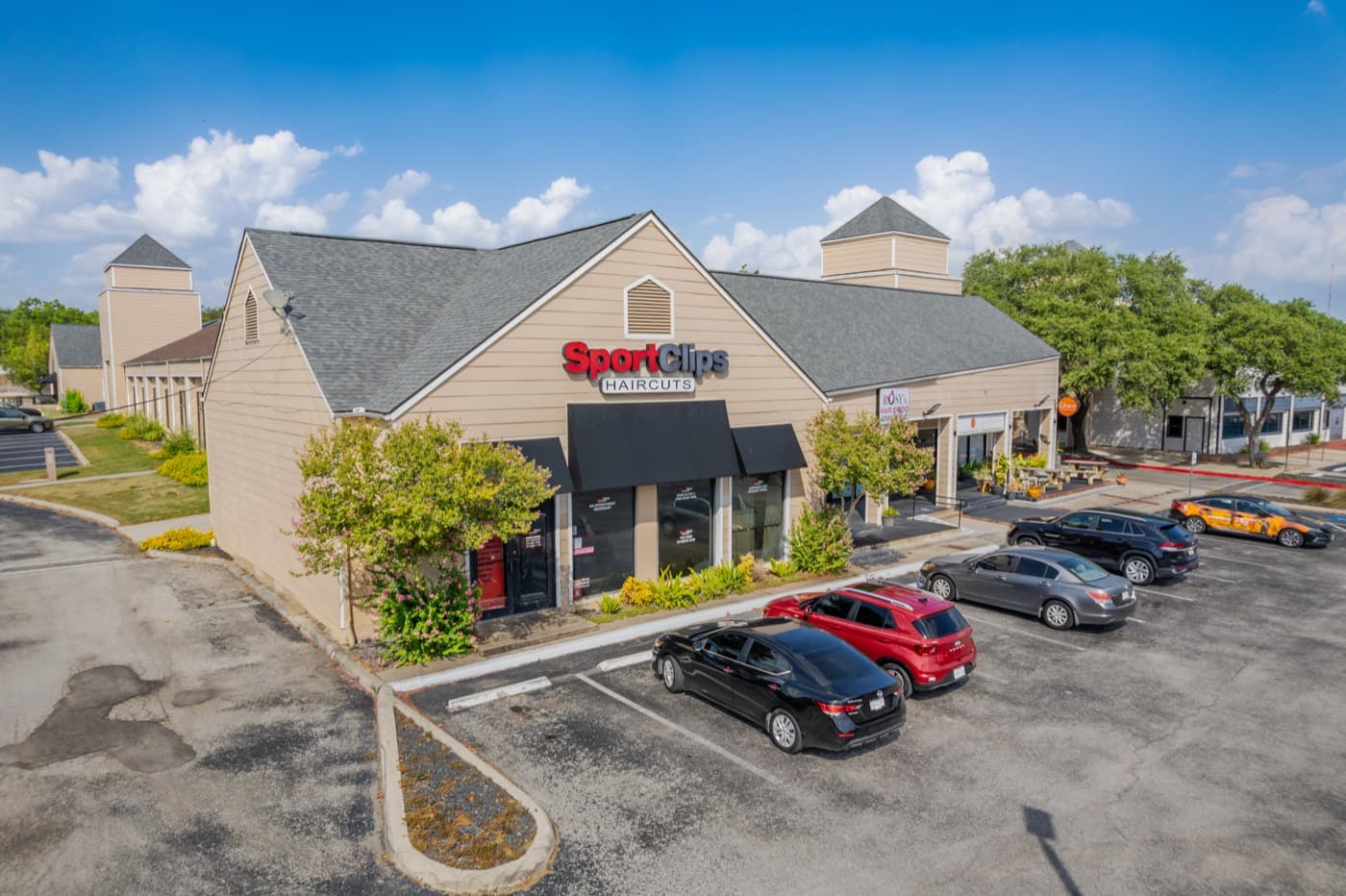 Retail building with a gabled roof and landscaping in a shopping center lot