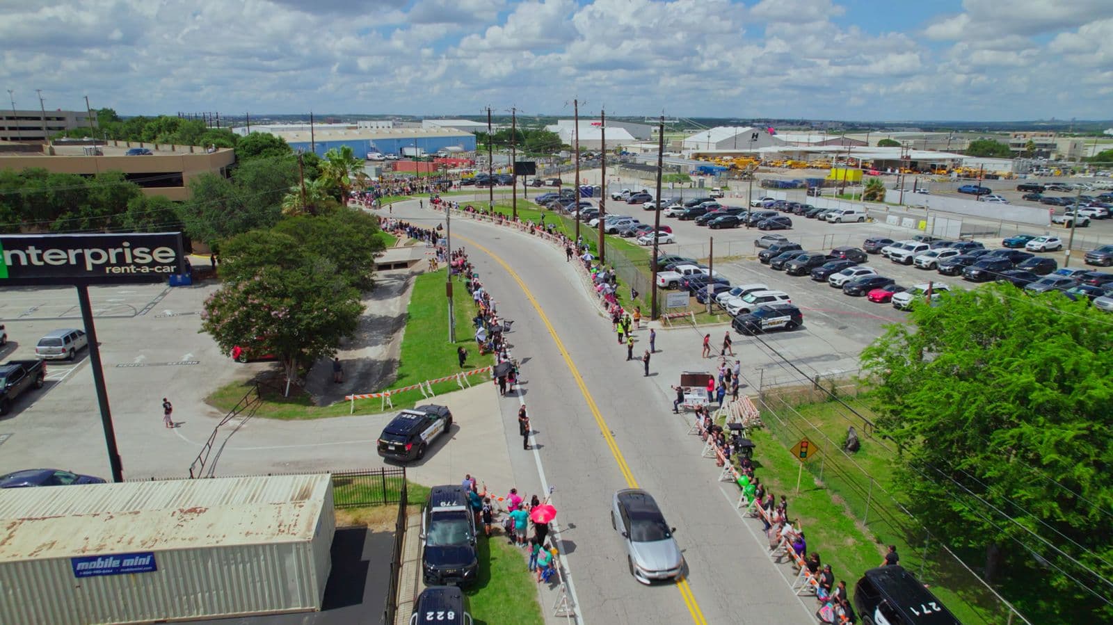Aerial view of a parade route lined with spectators beside a parking lot